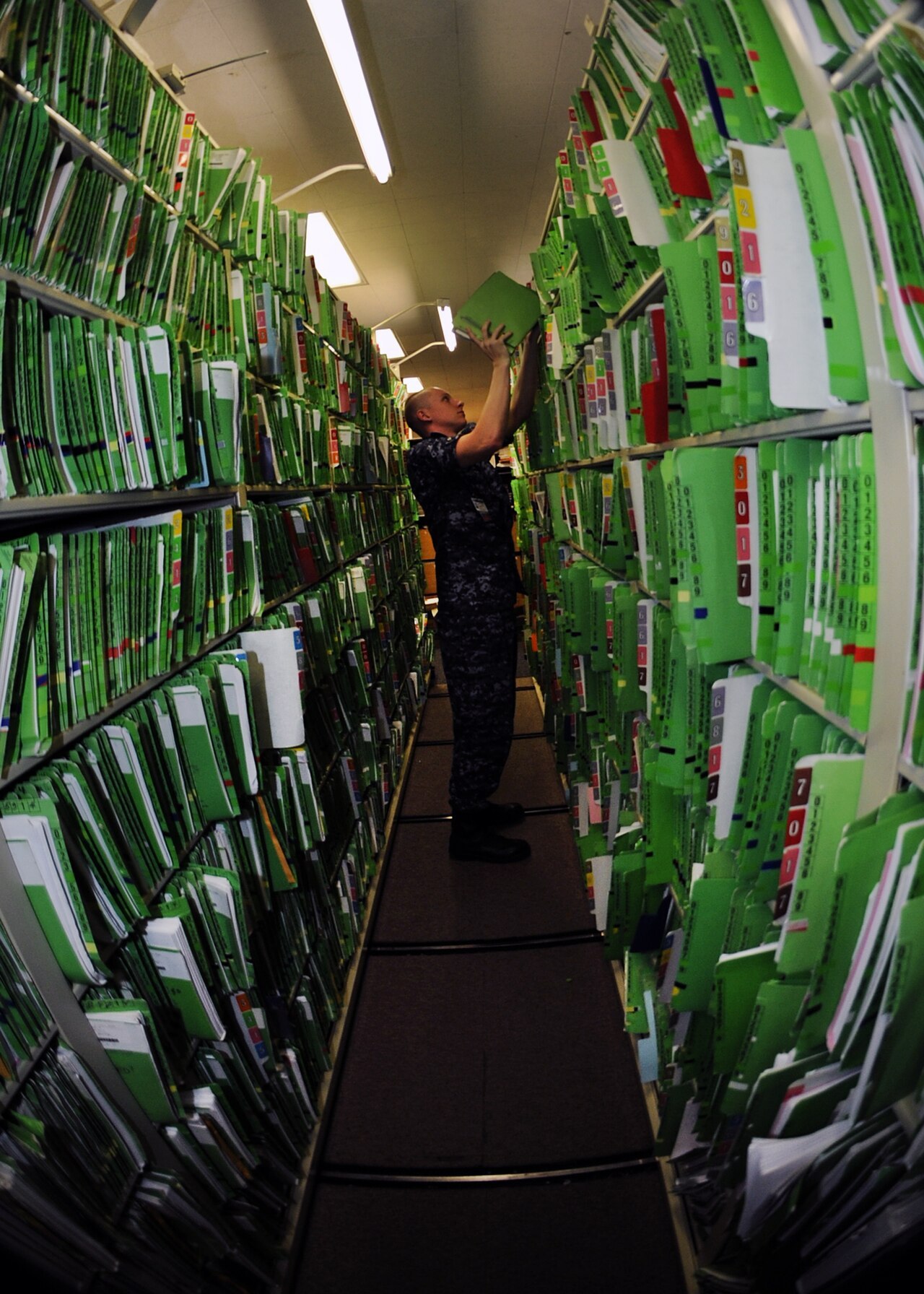 A hospital corpsman filing paper inpatient records in a records department