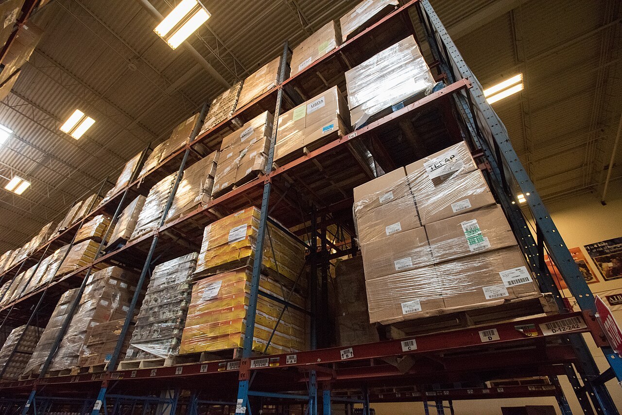 Warehouse racking stacked high with shrink-wrapped pallets of boxes
